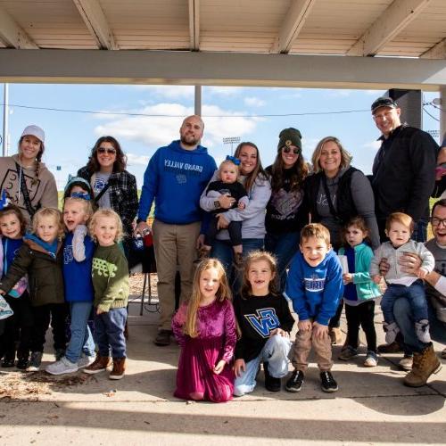 A group of family, friends and kids smile for a photo during Homecoming 2023