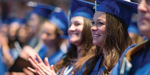 Students sitting in their cap and gown at commencement