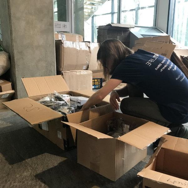 person hunched over moving boxes, packing them