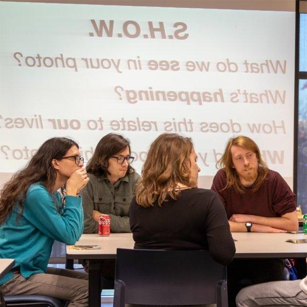 four students at table with projection on screen in background, 要求显示, 我们在你的照片里看到了什么?