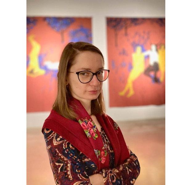 portrait of Iryna Bilan in an art gallery, two works of colorful art behind her